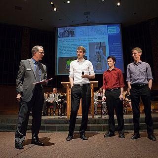 Photo of John McVay talking to three students up front at the church